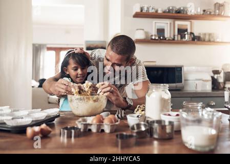 Die Liebe zur Familie ist chaotisch. Aufnahme eines Vaters, der seiner Tochter beibringt, wie man zu Hause in der Küche backen kann. Stockfoto