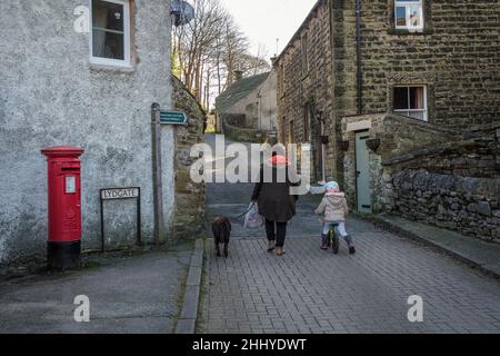 Menschen aus der Region, die einen Hund im Lydgate in Eyam, dem „Pestdorf“, Peak District National Park, Derbyshire, spazieren gehen Stockfoto