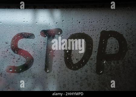 WORTSTOPP auf nassem beschlagenen Glas mit Tropfen an einem regnerischen Tag geschrieben Stockfoto