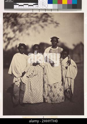 [Family Group] 1863 Désiré Charnay Französisch aufgrund der mangelnden Zusammenarbeit der Regierung unter der Führung der Hova, der mächtigsten ethnischen Gruppe Madagaskars, beschränkte sich Charnays Erkundung der Insel auf einige Ausflüge rund um den Hafen von Tamatave an der Ostküste. Dieses Foto einer Betsimitsaraka-Familie wurde auf Nossi-Malaza, der Insel der Freuden am Nossi-be-See, einer Lagune südlich von Tamatave, aufgenommen. Charnay bemerkte den herzlichen Empfang, den er dort erhielt, die schlaksige Schönheit der Frauen und die allgemeine Atmosphäre des Wohlstands. Er beschrieb die geflochtenen Haare der Frauen und ihre anmutigen Stockfoto