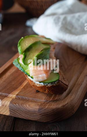 Roggen-Sandwich mit geräuchertem Lachs und Quark auf einem hölzernen Hintergrund. Stockfoto