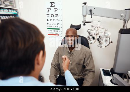 Einen Schritt von besserer Sicht entfernt. Aufnahme eines jungen Mannes, der einen von einem Optiker durchgeführten Augentest durchführte. Stockfoto