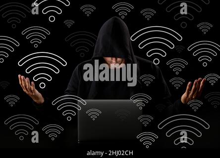 Mann mit Laptop, der Wi-Fi auf dunklem Hintergrund verwendet Stockfoto