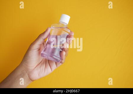 Halten Sie einen Mundspülbehälter mit der Hand auf blauen Hintergrund Stockfoto