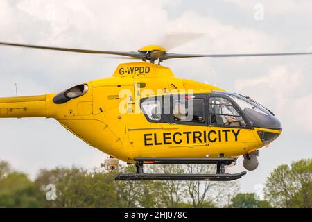 Nahaufnahme des gelben WPD-Hubschraubers (der in der Stromverteilungsbranche für Netzwartung/-Reparatur und Inspektion von Stromleitungen verwendet wird), der abfliegt. Stockfoto