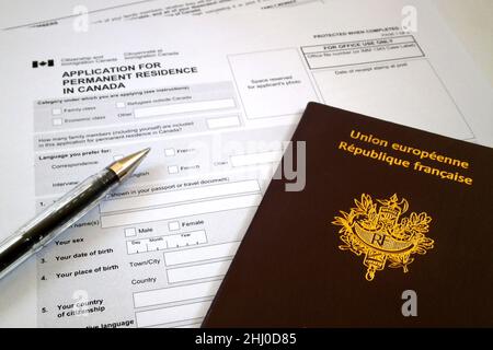 Einen Stift und einen französischen Pass oben auf einem Antragsformular für einen dauerhaften Aufenthalt in Kanada. Stockfoto