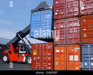 Im Hafen gestapelte Versandcontainer. Hydraulischer Gabelstapler, der globale Frachtcontainer auf dem Hafenladebereich des Industriehafens stapelt. USA Stockfoto