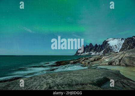 Oksen Berg (auch bekannt als die "Teufelszähne"), an einer kalten Winternacht mit Nordlichtern (Senja, Norwegen) ESP: Montaña Oksen y auroras boreales Stockfoto