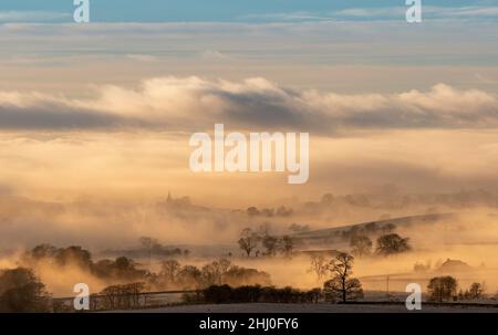 Der Turm der All Saints Church, die Pfarrkirche von Burton in Lonsdale, North Yorkshire, ragt über eine spektakuläre Wolkeninversion in der späten af hinaus Stockfoto