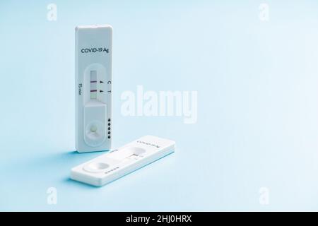 Positiver Covid-19-Antigentest. Coronavirus-Antigen-Schnelltest auf blauem Hintergrund. Stockfoto