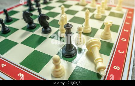 Ein Schachbrett mit Stücken. Das Spiel endete mit der Niederlage des weißen Königs. Das Konzept der Strategie im Geschäft Stockfoto