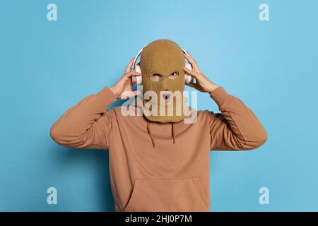 Studioaufnahme eines jungen anonymen Mannes, Studenten mit Balaclava isoliert auf blauem Hintergrund. Konzept der Emotionen, Mode Stockfoto