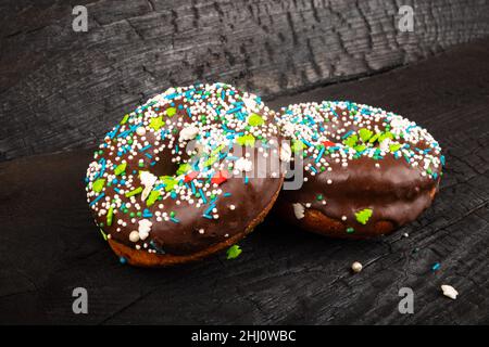 2 glasierte Schokoladendonuts auf dunklem Grund. Süßes, leckeres Brötchen. Stockfoto