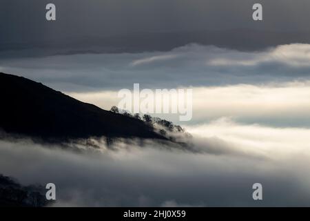 Stimmungsvolle Szenen vom Kirkstone Pass mit Blick über Windermere, während eine Wolkeninversion das Tal hinaufkriecht, Cumbria, Großbritannien. Stockfoto