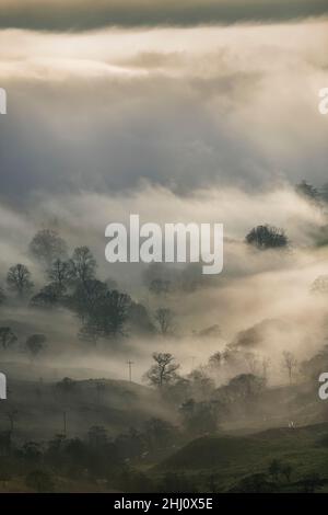 Stimmungsvolle Szenen vom Kirkstone Pass mit Blick über Windermere, während eine Wolkeninversion das Tal hinaufkriecht, Cumbria, Großbritannien. Stockfoto