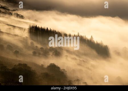 Stimmungsvolle Szenen vom Kirkstone Pass mit Blick über Windermere, während eine Wolkeninversion das Tal hinaufkriecht, Cumbria, Großbritannien. Stockfoto