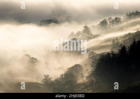 Stimmungsvolle Szenen vom Kirkstone Pass mit Blick über Windermere, während eine Wolkeninversion das Tal hinaufkriecht, Cumbria, Großbritannien. Stockfoto