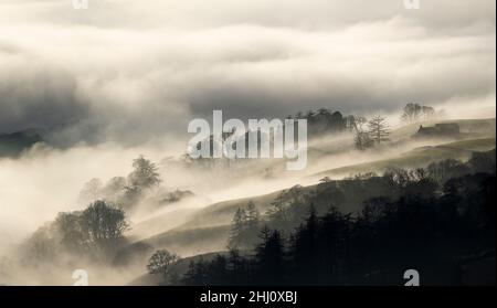 Stimmungsvolle Szenen vom Kirkstone Pass mit Blick über Windermere, während eine Wolkeninversion das Tal hinaufkriecht, Cumbria, Großbritannien. Stockfoto