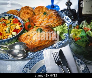 Zwei Gitterscheiben auf einer blau-weißen Schüssel mit Salat, Mais-Gurken, Tomaten, rotem Paprika, Salat, Petersilienmesser und weißer Serviette Stockfoto