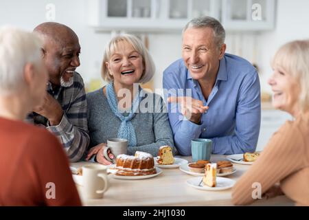 Multirassische Gruppe glücklicher älterer Menschen, die Tee mit Kuchen trinken Stockfoto
