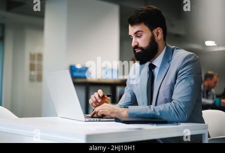 Ruhiger Geschäftsmann, der auf dem Laptop schreibt und Arbeit macht Stockfoto