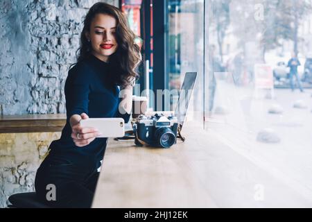 Fröhliche Freiberuflerin mit Smartphone im Café Stockfoto