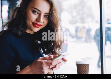 Lächelnde Dame mit Pappbecher im Café Stockfoto