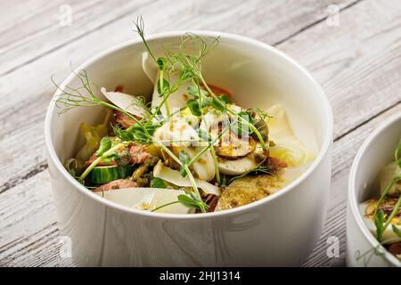 Fischsalat aus nächster Nähe mit leicht gesalzenem Lachs, Ei, Käse, frischen Kräutern und würziger Senfsauce. Vorbereitet in der heimischen Küche. Lecker und gesund Stockfoto