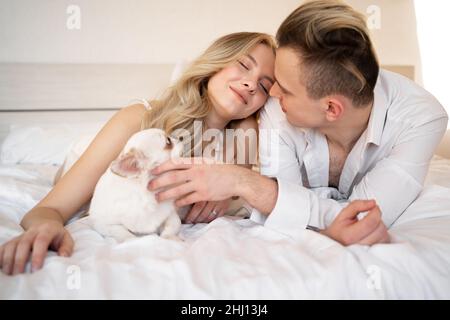 Süßes europäisches Paar mittleren Alters mit chihuahua Hund im Schlafzimmer auf dem Bett. Mann und Frau mit Haushund gemütlichen Lebensstil in der realen Welt. Stockfoto