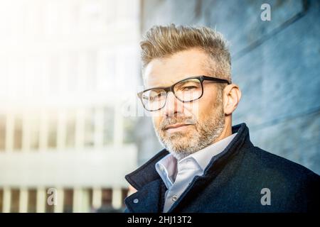 Porträt eines glücklichen, reifen und lächelnden Geschäftsmannes im Freien - älterer Mann mit Bart und Brille Stockfoto