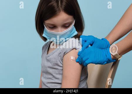 Kind Wird Gegen Covid-19 Geimpft. Arzt, Der Nach Der Impfstoffinjektion Eine Selbstklebende Bandage Anwendet. Kinder Covid-19 Prävention Impfung und Schutz. Antivirale Immunisierung Der Bevölkerung. Stockfoto