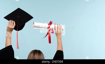 Rückansicht Unerkennbare Frau trägt Zeremonie Robe Holding Zertifikat und Werfen Graduation Cap auf blauem Hintergrund. Mädchen feiert Abschluss und bekommen Diplom. Graduate Cap und Degree Paper Stockfoto