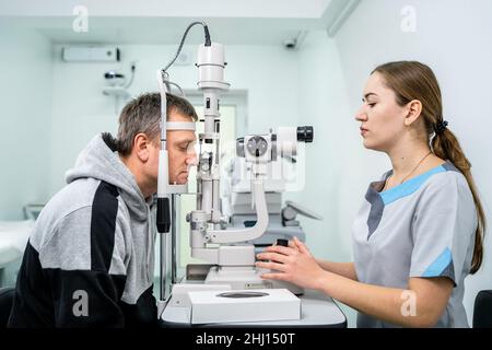 Augenarzt und Patienten-Tests Sehvermögen. Mann, der Augenuntersuchung mit Optiker macht. Augenarzt mit Apparaten für Augenuntersuchungen in der Klinik Stockfoto