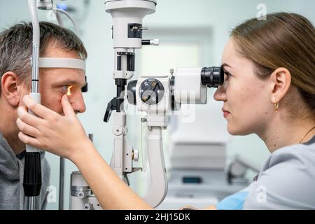 Augenarzt und Patienten-Tests Sehvermögen. Mann, der Augenuntersuchung mit Optiker macht. Augenarzt mit Apparaten für Augenuntersuchungen in der Klinik Stockfoto