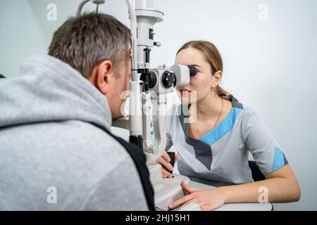 Arzt und Patient in der Augenklinik. Männlicher Patient, der die Sehkraft mit speziellen Augengeräten überprüft. Optometrie-Konzept. Mann, der einen Optiker besucht. Patient Stockfoto