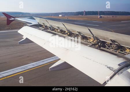 Der Flügel eines Passagierflugzeugs mit Luftbremsen und Mechanisierung unter ihnen an den Klappen nach der Landung Stockfoto