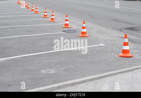 Verkehrskegel auf der Straße. Geschlossener PKW-Parkplatz mit weißer Markierung und Verkehrskegel auf der Straße gebrauchter Warnschild auf der Straße Stockfoto