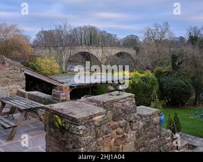 Blick auf die Brücke über den Fluss Ure über einen privaten Garten, West Tanfield. Stockfoto