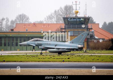 Wittmund, Deutschland. 26th Januar 2022. Ein Eurofighter Typhoon-Kämpfer der Luftwaffe fährt vor dem Turm des Luftwaffenstützpunktes Wittmundhafen über die Asphalt. Aufgrund einer umfassenden Sanierung des Flugstützpunktes in Wittmund, Ostfriesland, verlegt die Bundeswehr vorübergehend 19 Eurofighter von dort auf den Stützpunkt Laage südlich von Rostock in Mecklenburg-Vorpommern. Quelle: Hauke-Christian Dittrich/dpa/Alamy Live News Stockfoto