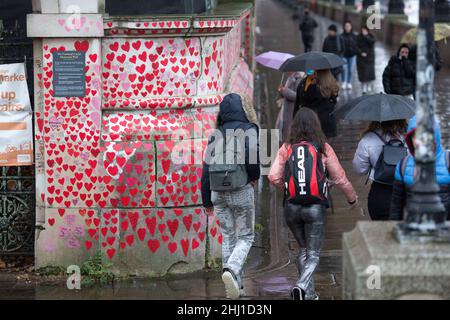 Fußgänger werden an der National Covid Memorial Wall in London neben roten Herzen, die diejenigen darstellen, die an Covid-19 gestorben sind, gesehen. Stockfoto