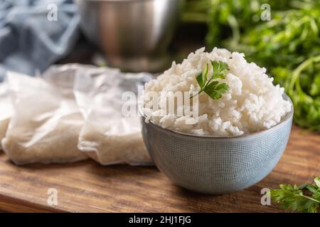 Gekochter Reis in einer Schüssel mit rohem Reis in Plastick-Tüten. Stockfoto