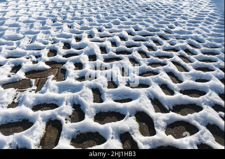 Sich wiederholende Fischgrätschneemuster, die durch Leitungsunterschiede entstehen, Wärmedämmung in der Auffahrt dunkle Bereiche werden sich durch Sonneneinstrahlung schneller erwärmen Stockfoto