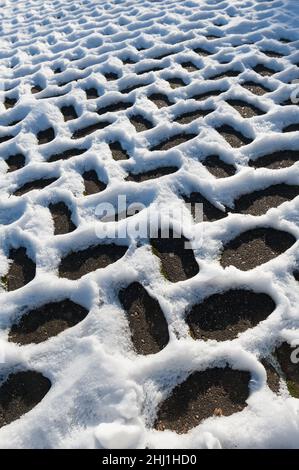 Sich wiederholende Fischgrätschneemuster, die durch Leitungsunterschiede entstehen, Wärmedämmung in der Auffahrt dunkle Bereiche werden sich durch Sonneneinstrahlung schneller erwärmen Stockfoto