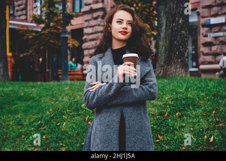 Jugendliche schöne Frau in warmer Kleidung mit Kaffee zum Mitnehmen Stockfoto