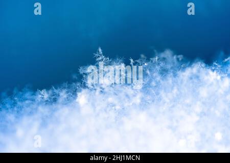 Viele kleine Schneeflocken im Schnee, blauer Hintergrund, Nahaufnahme Stockfoto