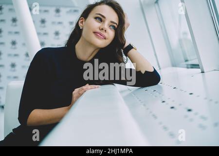 Junge Frau, die auf dem weißen Sofa sitzt und aufschaut Stockfoto
