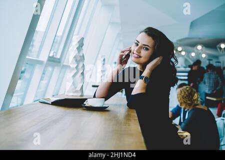 Glückliche Frau, die am Telefon sprach und Haare berührte Stockfoto