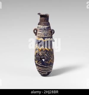 Glas-Alabastron (Parfümflasche) Ende 6th–5th Jahrhundert v. Chr. Griechisch, östliches Mittelmeer Durchscheinendes Kobaltblau, mit Griffen in gleicher Farbe; Trails in opak-weiß und opak-gelb.Dünne, nach innen abfallende Randscheibe; hoher, schräg, zylindrischer Hals, Mit markierter horizontaler Linie an der Basis; kurze, abgerundete Schulter; länglicher ovaler Körper mit nach oben gezogenem Kegel; konvexer Boden; unter der Schulter zwei vertikale Ringgriffe mit geklopften Schwänzen, über Trails angebracht. Eine weiße Spur am Rand der Randscheibe befestigt; Eine andere Anwendung unten shodder und Wunde nach unten in enger Spirale auf den oberen Teil des Körpers, wo eine zweite breiter Stockfoto