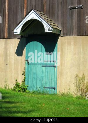 Stalltür, alt blau und grün, mit Schloss, Scharnieren und kleiner Dachabdeckung. Stockfoto