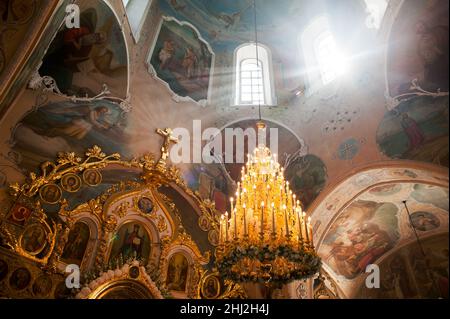 Orel, Russland - 28. Juli 2016: Interieur der russisch-orthodoxen Kirche. Sonnenstrahlen durch die Fenster, riesiger Kronleuchter mit Kerzen und Ikonen Stockfoto